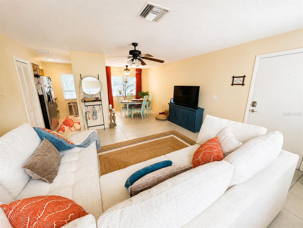 A living room with a white sectional sofa faces a television and a dining area — 6327 MIDNIGHT PASS RD ROAD UNIT 999, SARASOTA, FL