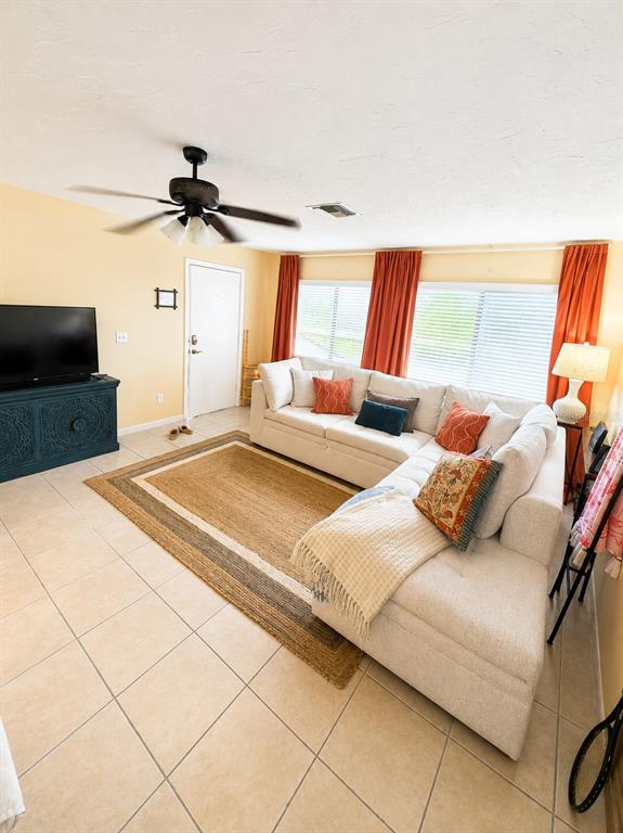 A living room features a sectional sofa, a television on a blue console, and tile flooring — 6327 MIDNIGHT PASS RD ROAD UNIT 999, SARASOTA, FL