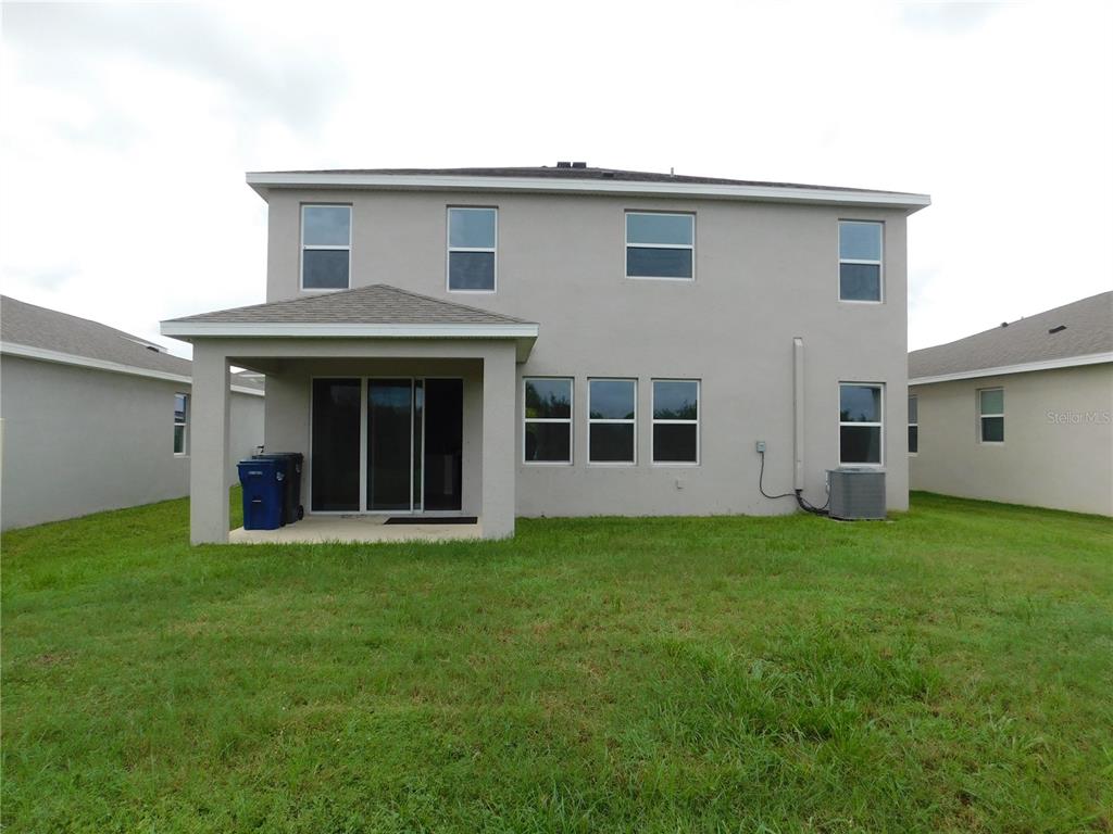 The rear exterior of a two-story house features a covered patio and a grassy yard — 3813 LIVELY CORAL PLACE, BRADENTON, FL