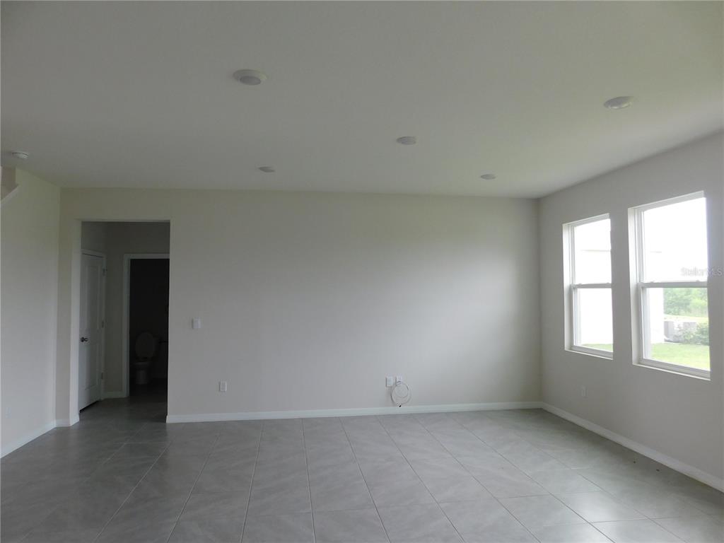 An empty room with gray tile flooring, recessed lighting, and two windows on the right — 3813 LIVELY CORAL PLACE, BRADENTON, FL