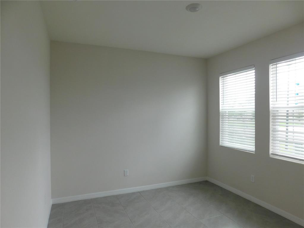 An empty room with light-colored walls, tile flooring, and two windows with white blinds — 3813 LIVELY CORAL PLACE, BRADENTON, FL