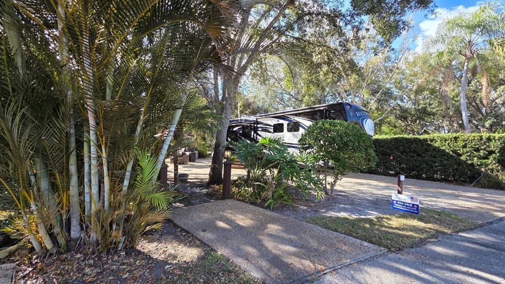 A large recreational vehicle is parked on a paved lot surrounded by trees and landscaping — 359 POSSUM PATH, RIVER RANCH, FL