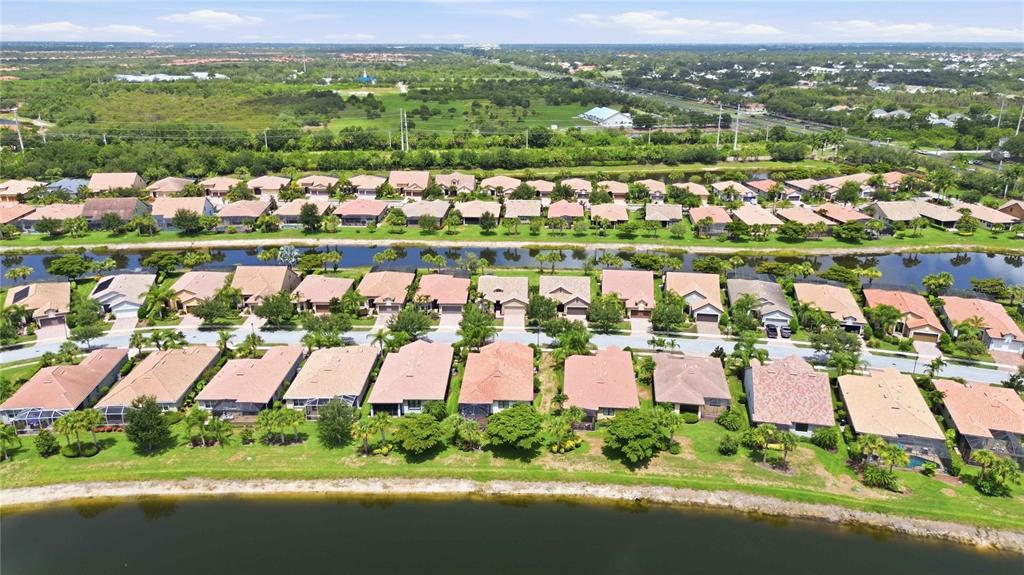 An aerial view shows a suburban neighborhood with rows of houses bordering a large lake — 19731 QUISTO STREET, VENICE, FL
