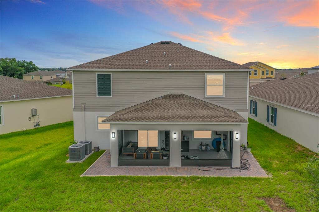 The rear exterior of a two-story house features a covered patio with a screened enclosure — 7542 HEADWATERS COURT, GROVELAND, FL