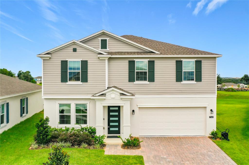A two-story suburban house with light gray siding, a white stucco base, and a garage — 7542 HEADWATERS COURT, GROVELAND, FL