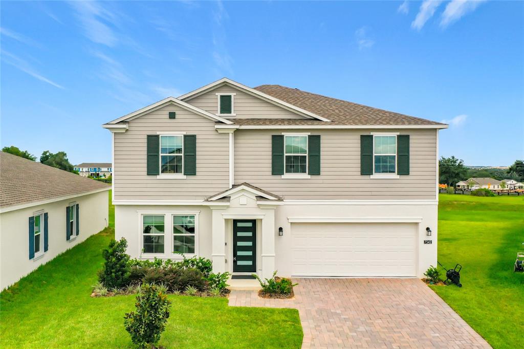 A two-story suburban house with light gray siding, a two-car garage, and a paved driveway — 7542 HEADWATERS COURT, GROVELAND, FL