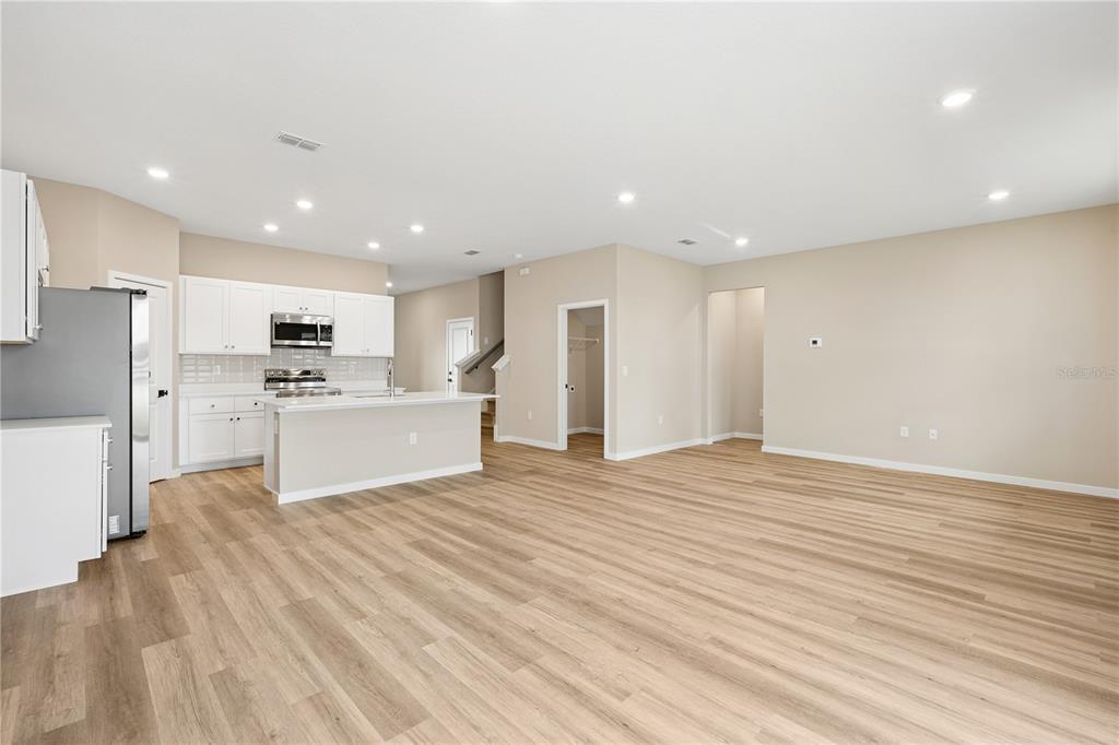 An open-concept kitchen and living area feature white cabinets, a kitchen island, and wood-look flooring — 4441 NW 37TH STREET ROAD, OCALA, FL