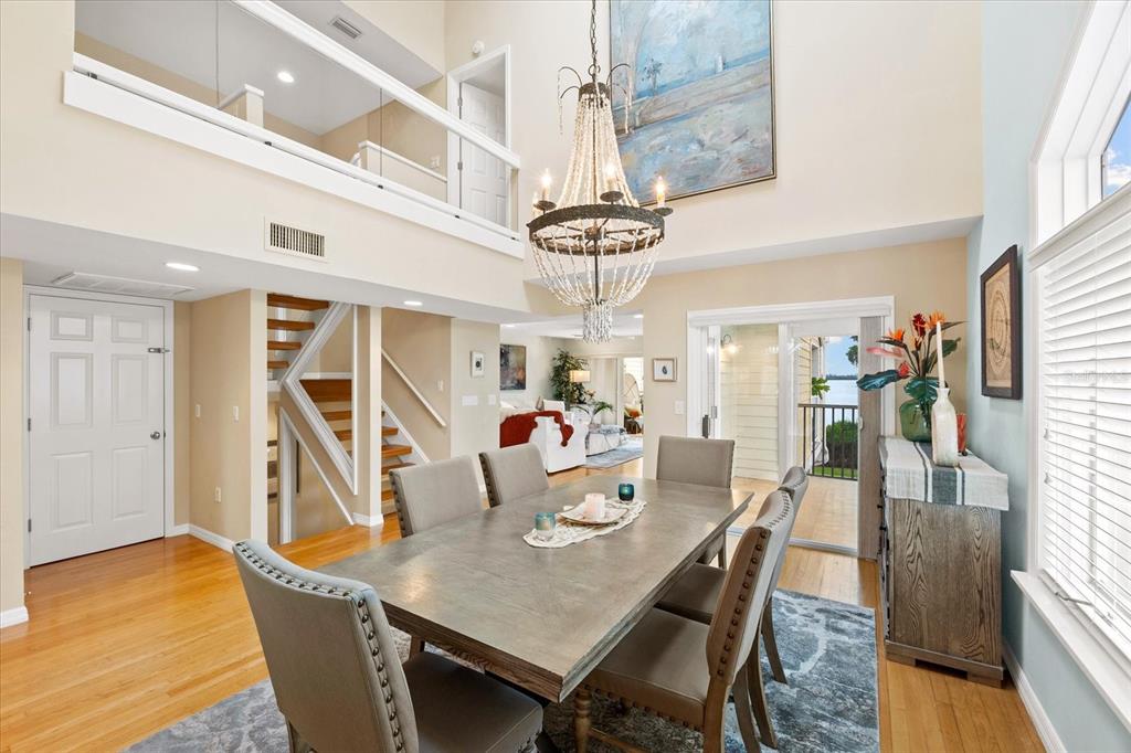 A dining room with a large wooden table, chandelier, and staircase leading to a loft — 76 TIDY ISLAND BOULEVARD, BRADENTON, FL