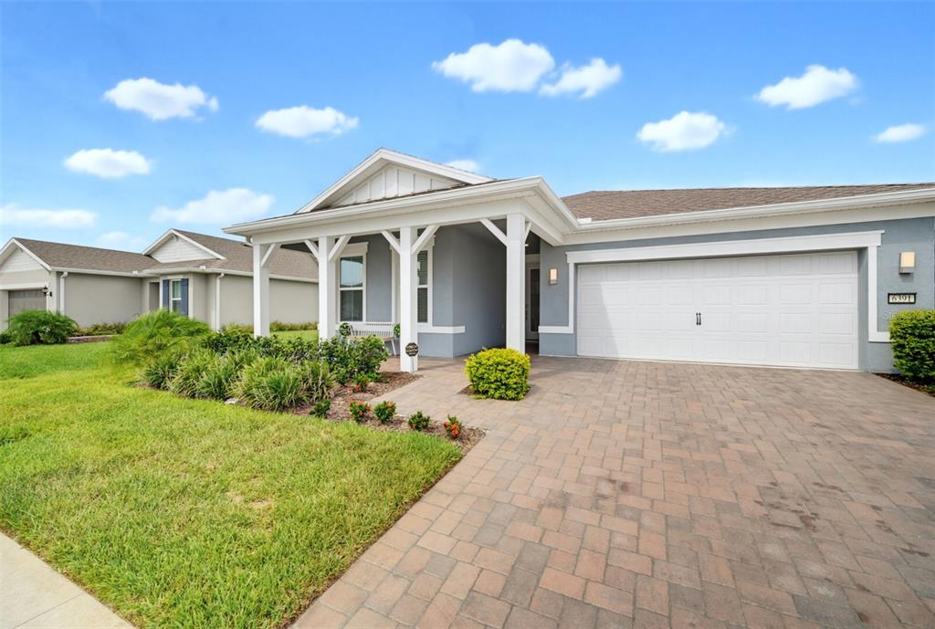 A single-story house with a gray exterior, white trim, a two-car garage, and paver driveway — 6391 SHIMMERING SHORES LANE, ST CLOUD, FL