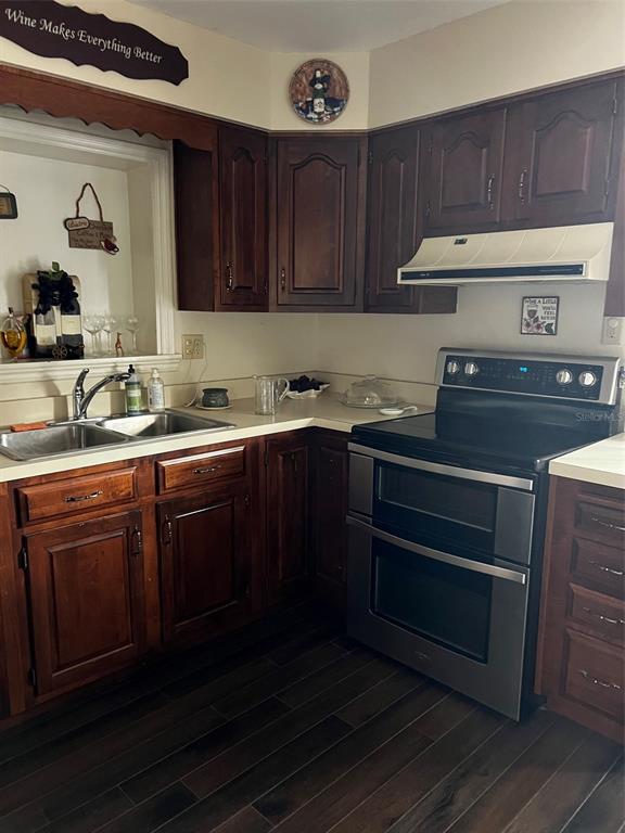 A kitchen features dark wood cabinets, stainless steel appliances, and a double-basin sink — 1220 S BAY STREET S, EUSTIS, FL