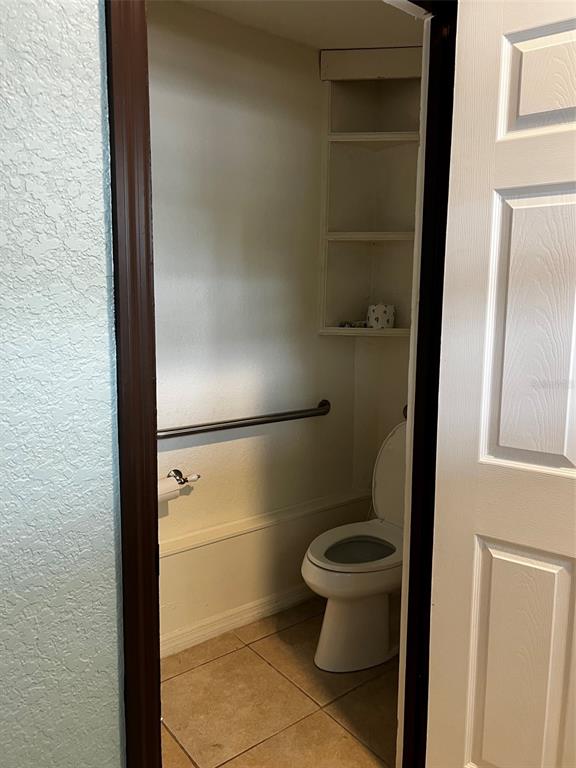 A small bathroom features a toilet, a grab bar, and built-in corner shelving — 1220 S BAY STREET S, EUSTIS, FL