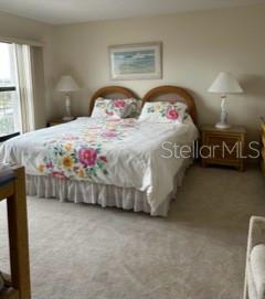 A bedroom features a bed with a floral comforter, two nightstands, and two table lamps — 1001 BENJAMIN FRANKLIN DRIVE UNIT 701, SARASOTA, FL