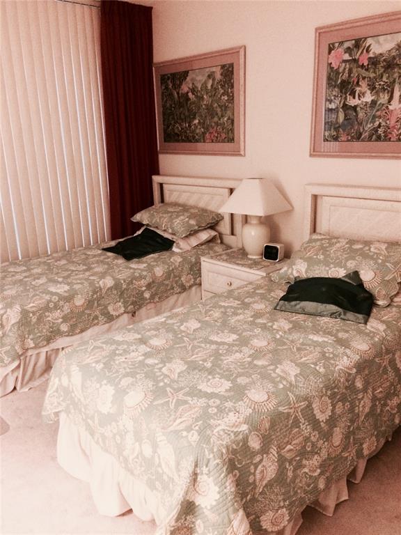 A bedroom with two twin beds featuring seashell-patterned quilts and framed tropical wall art — 1001 BENJAMIN FRANKLIN DRIVE UNIT 701, SARASOTA, FL