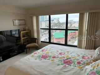 A bedroom features a floral bedspread, a television on a stand, and a large window view — 1001 BENJAMIN FRANKLIN DRIVE UNIT 701, SARASOTA, FL