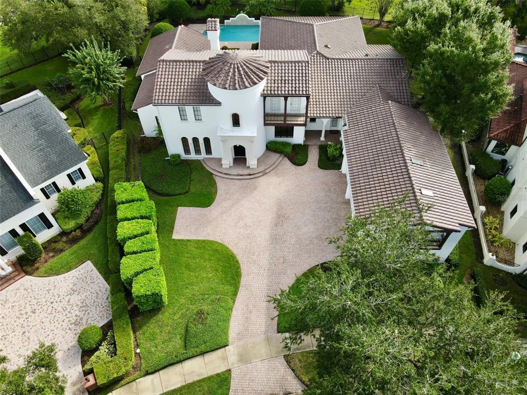 An aerial view shows a white Mediterranean-style house with a tiled roof, pool, and driveway — 234 ACADIA TERRACE, CELEBRATION, FL
