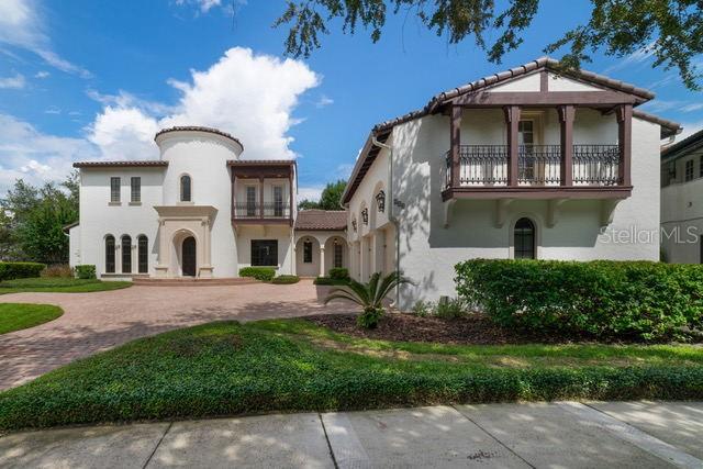 A large, two-story white stucco house with a turret and a balcony under a blue sky — 234 ACADIA TERRACE, CELEBRATION, FL