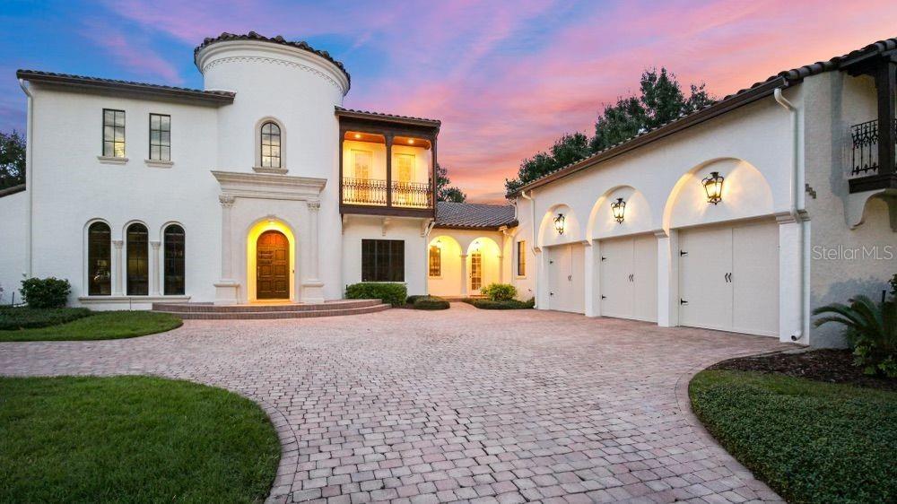 A white Mediterranean-style house features a circular tower, a wooden balcony, and a three-car garage — 234 ACADIA TERRACE, CELEBRATION, FL