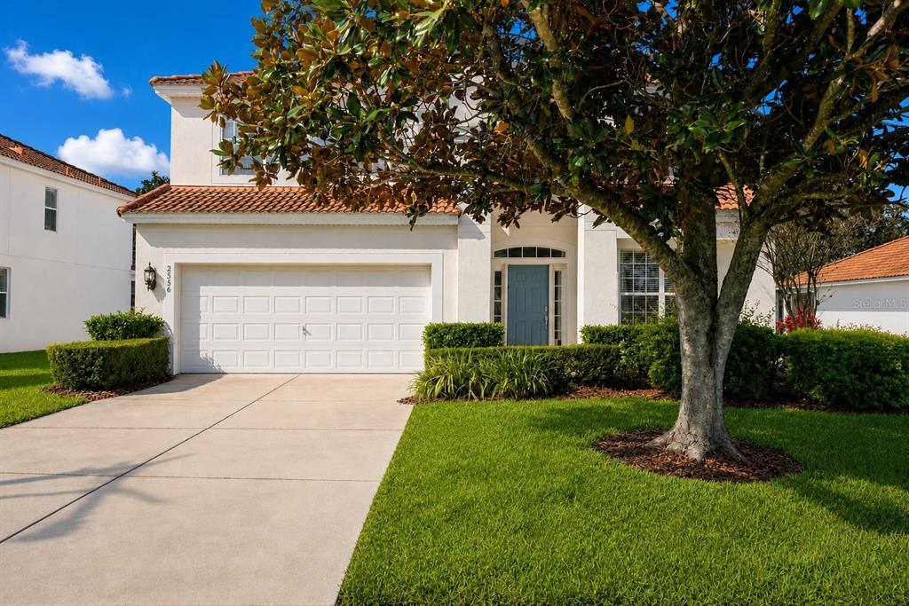 A two-story house with a white stucco exterior, a tile roof, and a front driveway — 2536 HOLTROCK STREET, KISSIMMEE, FL