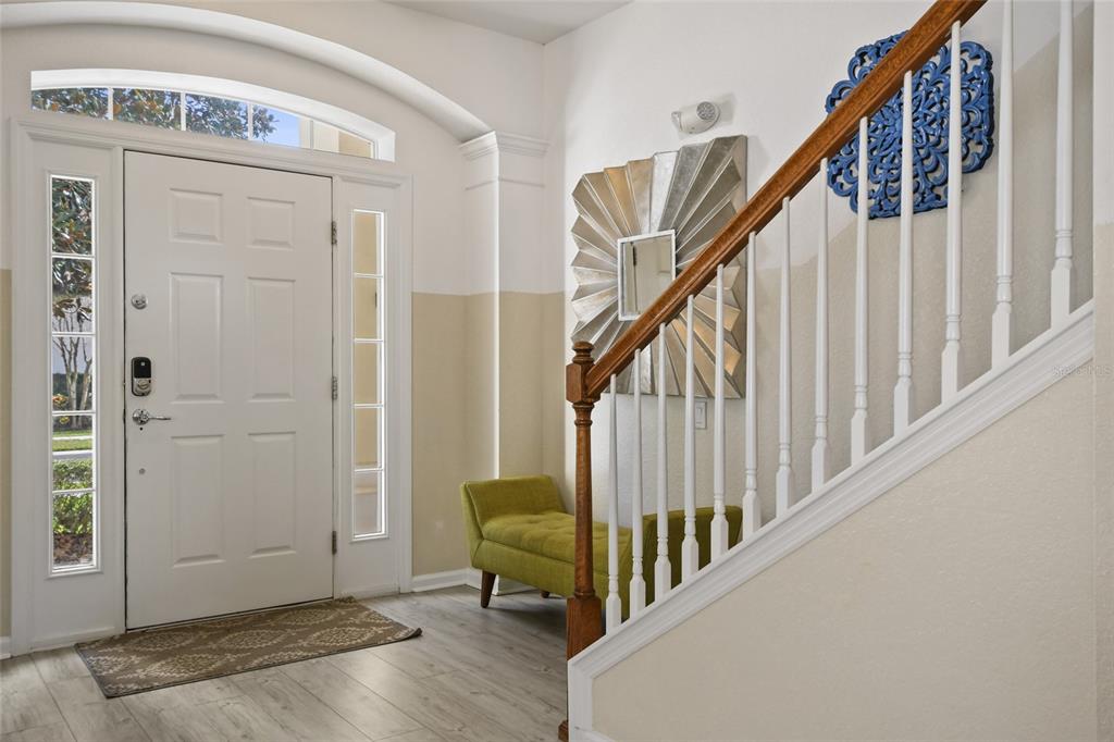An entryway features a white front door, a staircase with a wooden railing, and a bench — 2536 HOLTROCK STREET, KISSIMMEE, FL