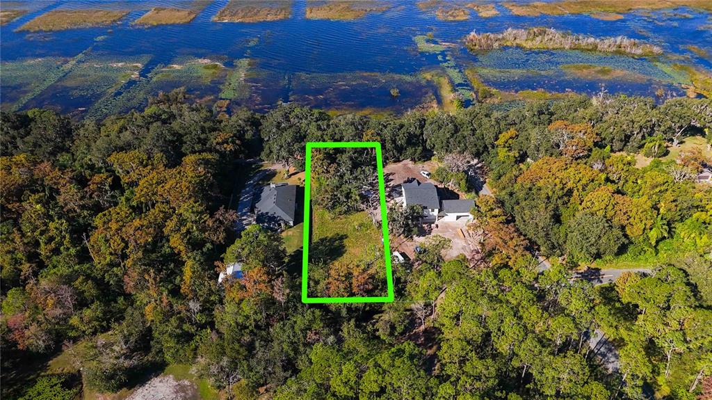 An aerial view shows a rectangular vacant lot situated between two houses near a lake — 0 LILLIAN BLACK ROAD, ST CLOUD, FL