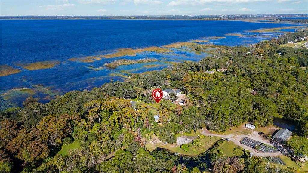An aerial view shows a house nestled in a wooded area beside a large lake — 0 LILLIAN BLACK ROAD, ST CLOUD, FL