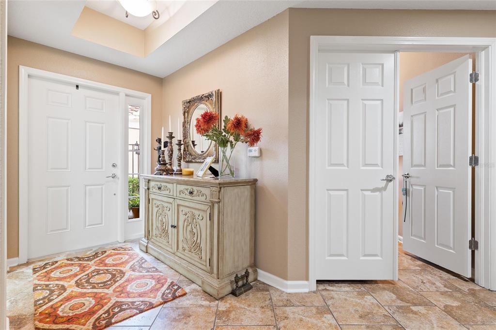 A foyer features a patterned rug, a decorative wooden sideboard, and white interior doors — 2061 CARRIAGE LANE UNIT 104, CLEARWATER, FL