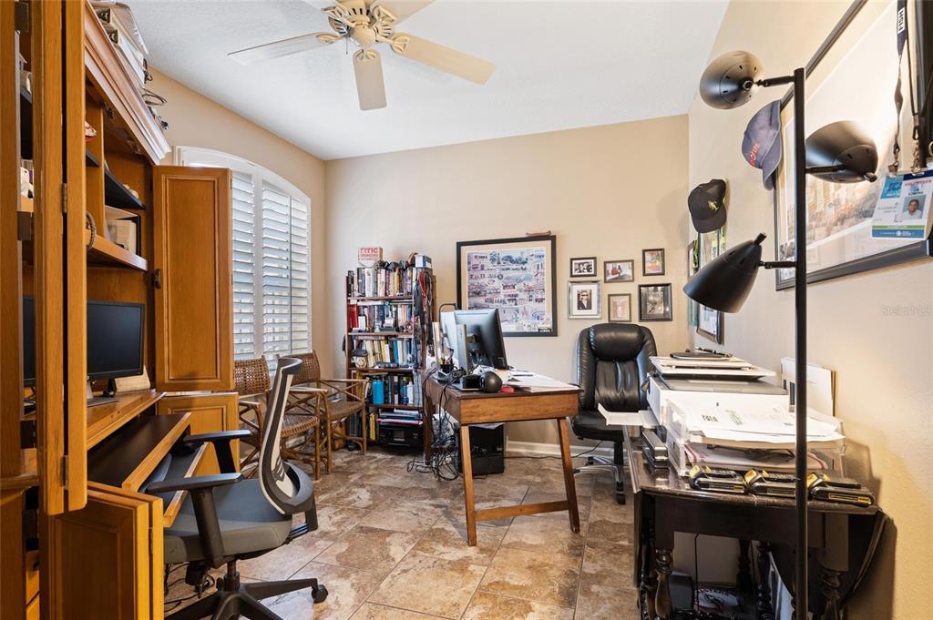 A home office features a wooden desk, a black office chair, and tile flooring — 2061 CARRIAGE LANE UNIT 104, CLEARWATER, FL