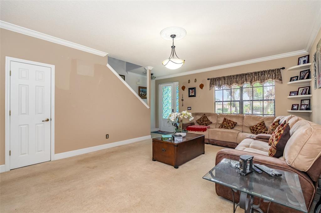 A living room with beige carpet, tan walls, a sectional sofa, and a wooden coffee table — 912 WHETSTONE PLACE, ROCKLEDGE, FL