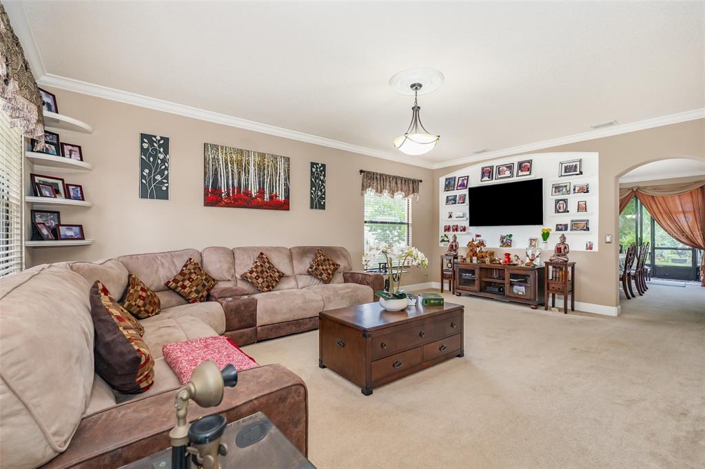 A living room features a large sectional sofa, a wooden coffee table, and a wall-mounted television — 912 WHETSTONE PLACE, ROCKLEDGE, FL