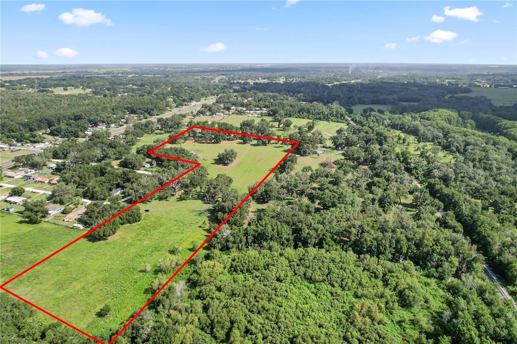 An aerial view shows a large, grassy, L-shaped plot of land outlined in red — 37952 CRYSTAL WAY, DADE CITY, FL