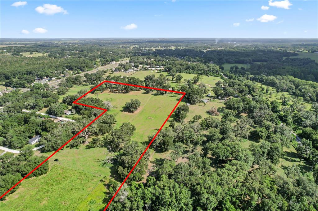 An aerial view shows a large, grassy plot of land outlined in red — 37952 CRYSTAL WAY, DADE CITY, FL