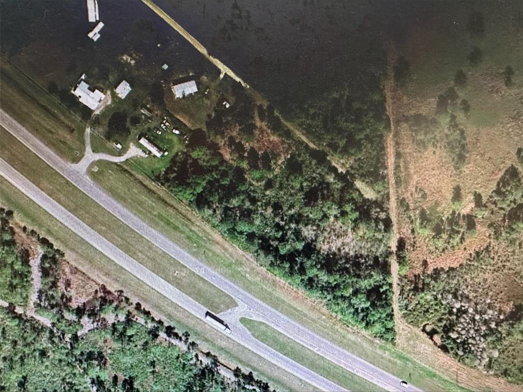 This aerial view shows a rural property with several buildings adjacent to a divided highway — E STATE ROAD 60, OKEECHOBEE, FL