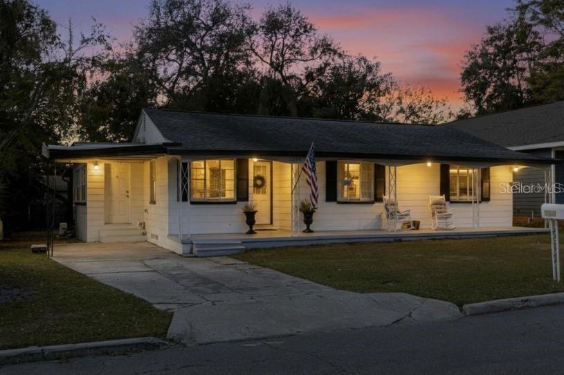 A single-story white house with a covered front porch and a concrete driveway at dusk — 1225 KING AVENUE, LAKELAND, FL