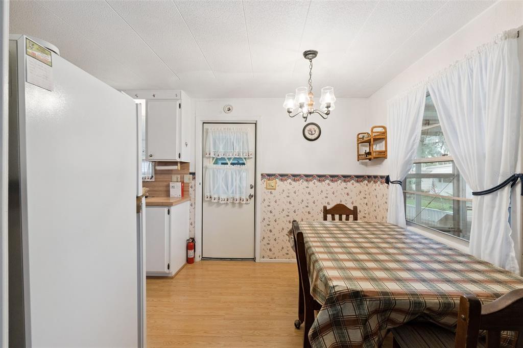 A kitchen and dining area features white cabinets, floral wallpaper, and a plaid tablecloth — 102 PARKLAND DRIVE, EUSTIS, FL