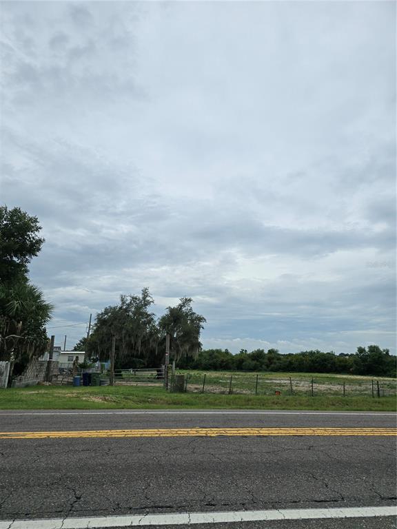 A view of a vacant, fenced grassy lot from across a paved road — LUCERNE PARK ROAD, WINTER HAVEN, FL