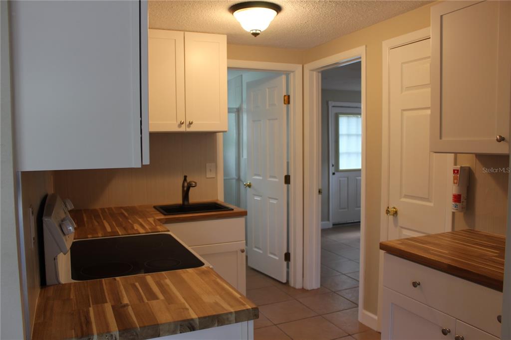 A kitchen features white cabinets, butcher block countertops, a black sink, and tile flooring — 4424 TERRY LOOP UNIT A, NEW PORT RICHEY, FL