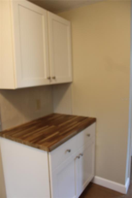 A kitchen area features white cabinets, a wood countertop, and a neutral wall — 4424 TERRY LOOP UNIT A, NEW PORT RICHEY, FL
