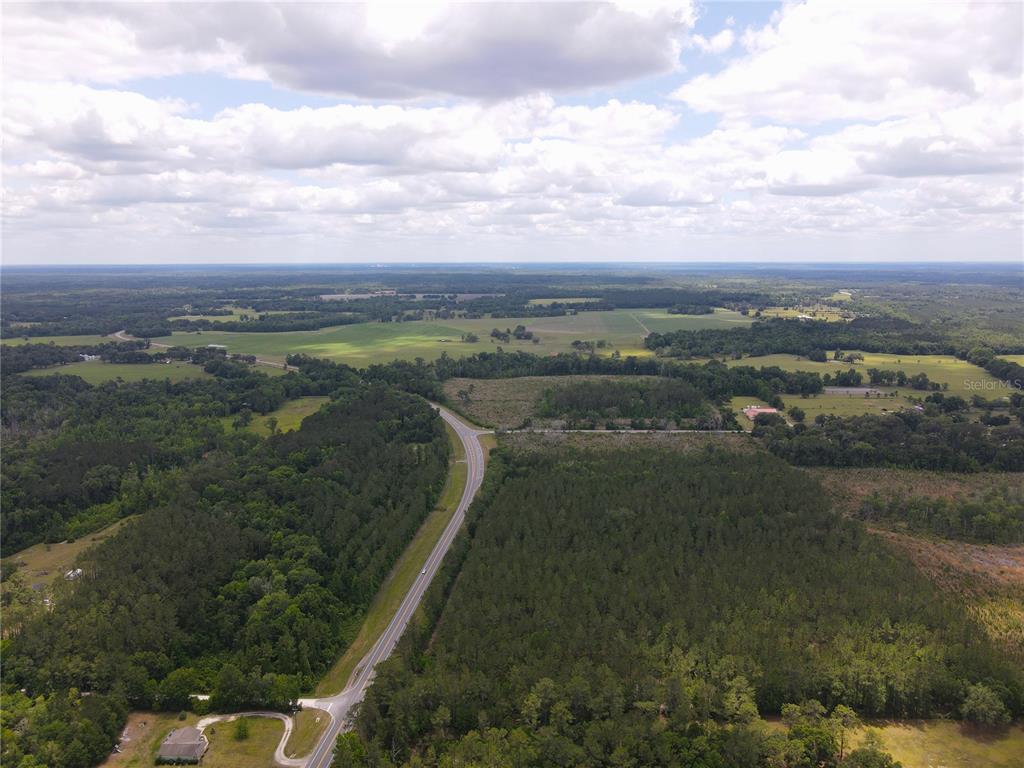 An aerial view shows a rural road winding through dense forests and open pasture land — TBD N STATE ROAD 121 UNIT 1, ALACHUA, FL