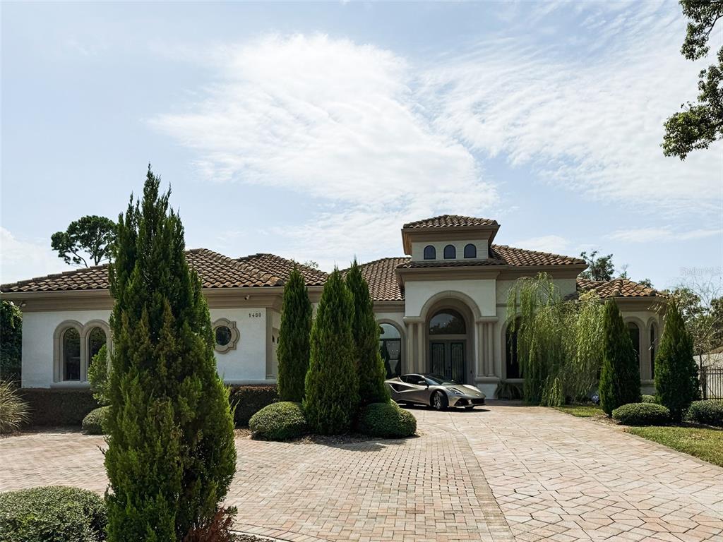 A single-story Mediterranean-style house with a tile roof, a paved driveway, and a parked sports car — 1480 HEMPEL AVENUE, WINDERMERE, FL