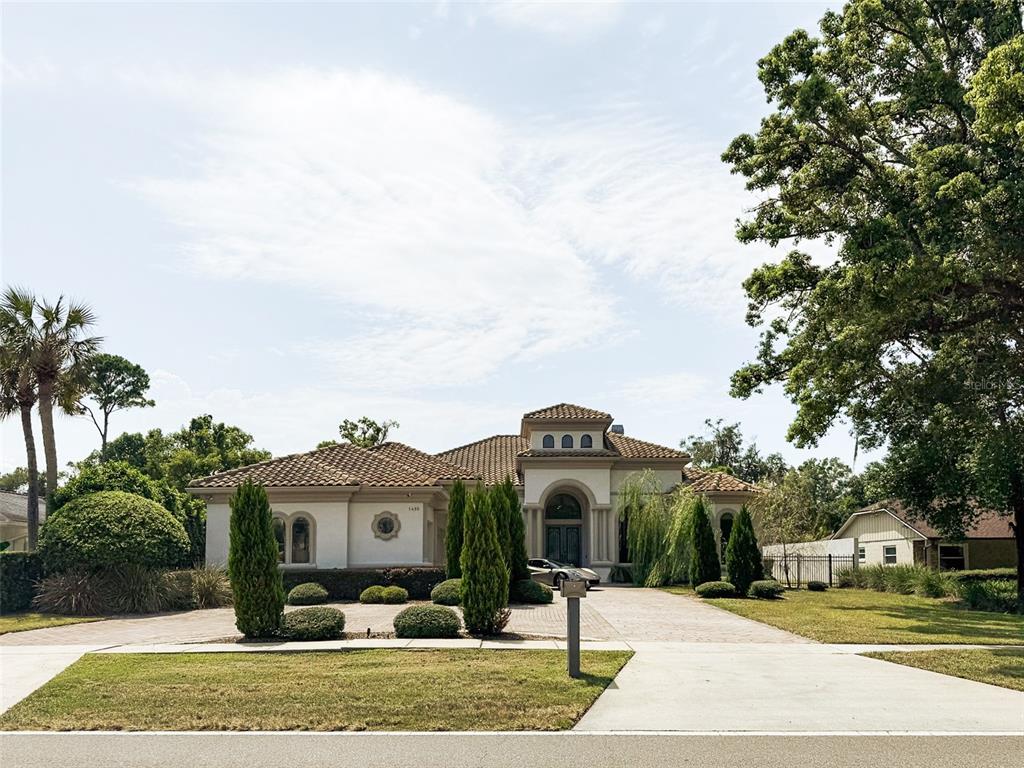 A single-story Mediterranean-style house with a tile roof and a sports car in the driveway — 1480 HEMPEL AVENUE, WINDERMERE, FL