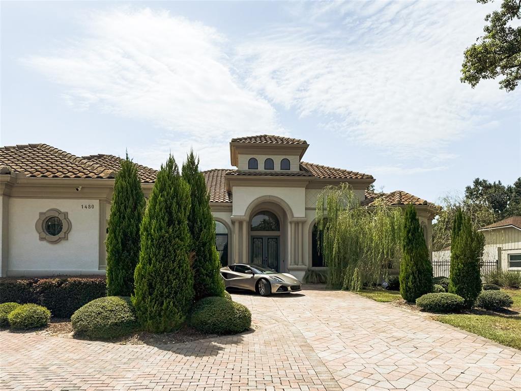 A silver sports car is parked on a paved driveway in front of a Mediterranean-style house — 1480 HEMPEL AVENUE, WINDERMERE, FL