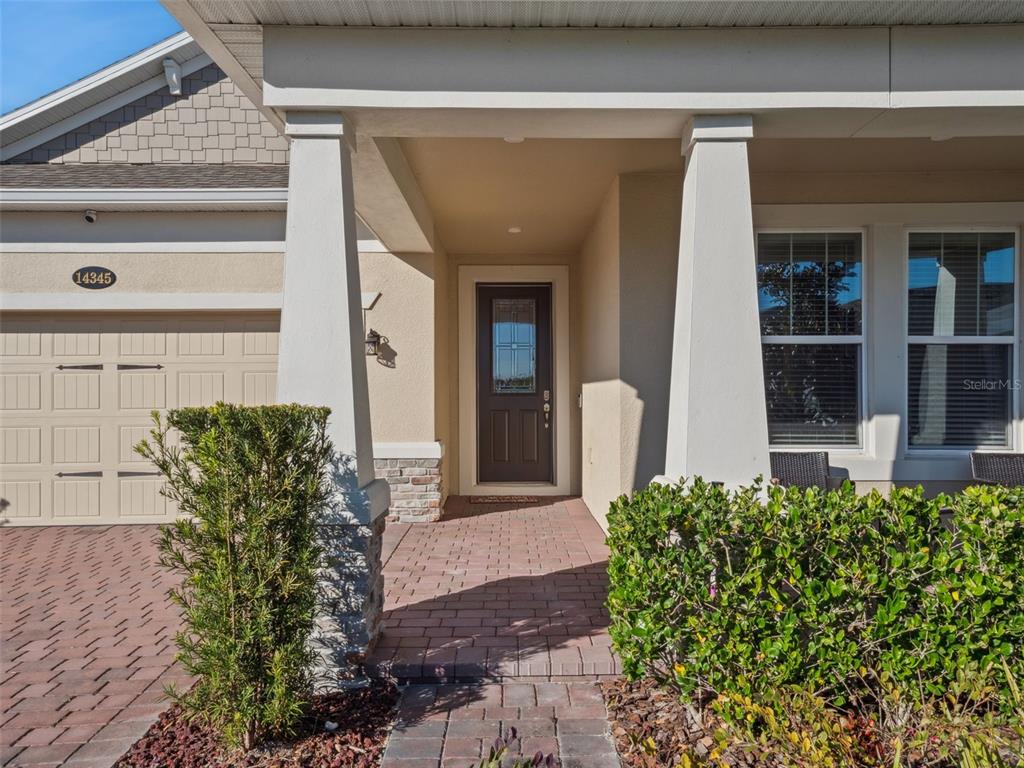The front entrance features a paved walkway, a dark door, and two white support columns — 14345 WABASSO LOOP, WINTER GARDEN, FL