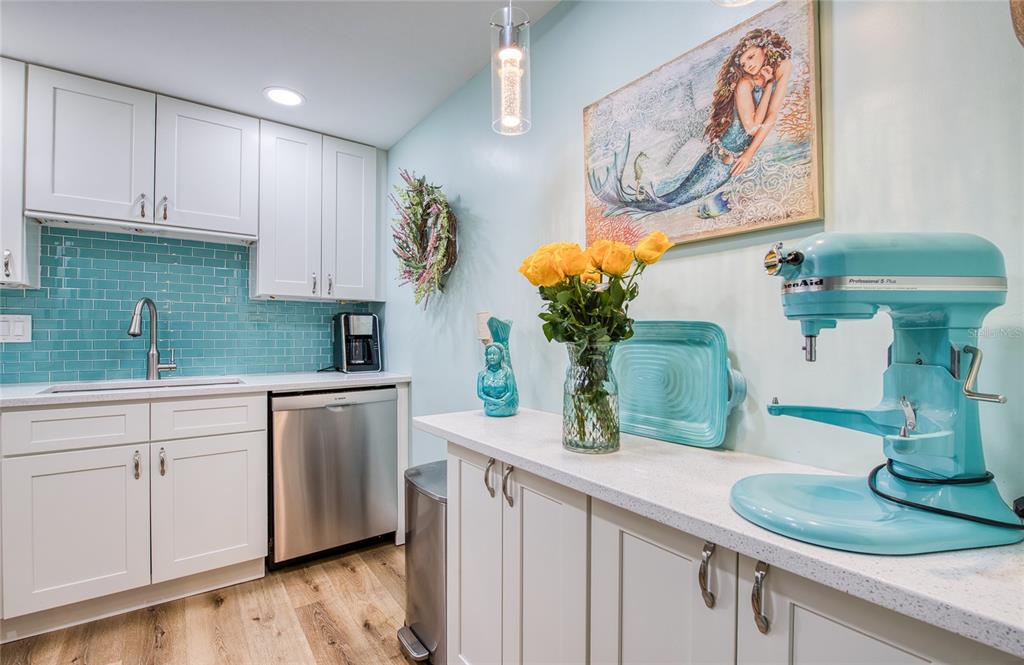 A kitchen features white cabinets, a teal subway tile backsplash, and a light blue wall — 10216 REGAL DRIVE UNIT 310, LARGO, FL