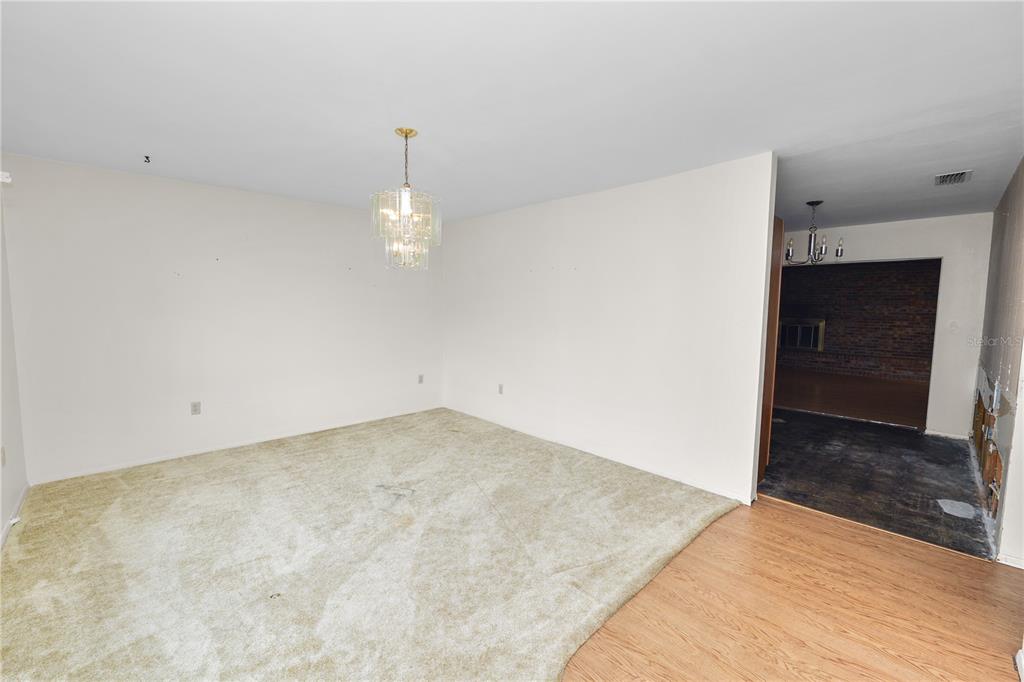 An interior view shows a carpeted dining area with a crystal chandelier adjacent to a kitchen — 760 MANOR DRIVE, BARTOW, FL