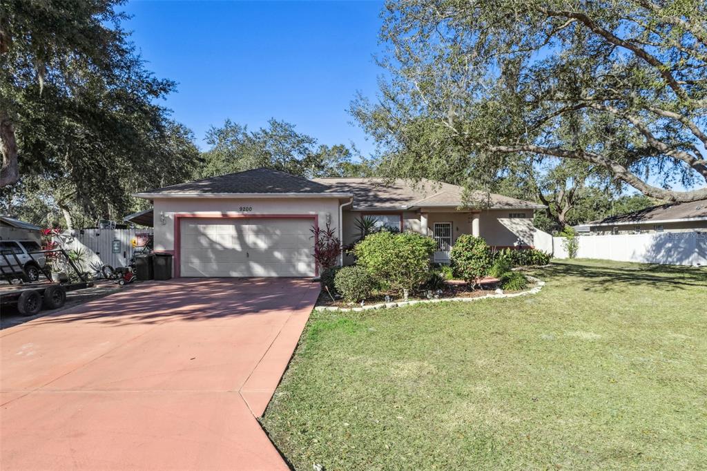A single-story house with a tan exterior, a two-car garage, and a large front yard — 9200 E WINDWOOD LOOP, INVERNESS, FL