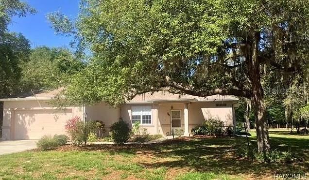 A single-story house with a two-car garage sits under a large, moss-draped oak tree — 9200 E WINDWOOD LOOP, INVERNESS, FL