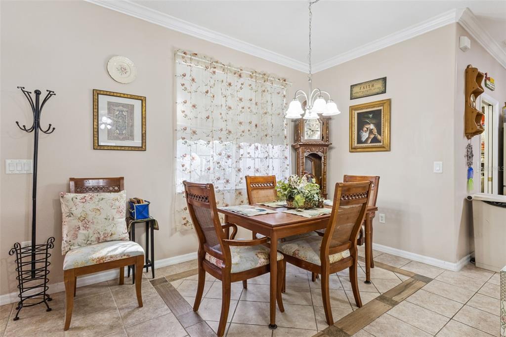 A dining room features a wooden table with four chairs, a grandfather clock, and tile flooring — 9200 E WINDWOOD LOOP, INVERNESS, FL