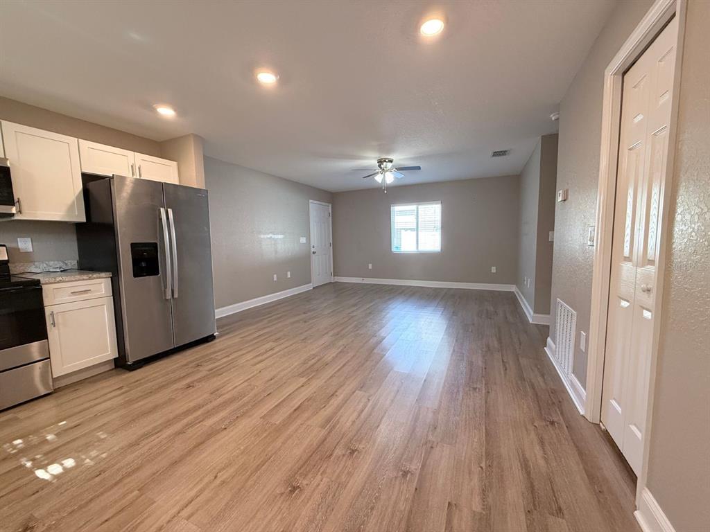 A kitchen with stainless steel appliances and white cabinets opens into a spacious living area — 1139 SYCAMORE STREET, LAKELAND, FL