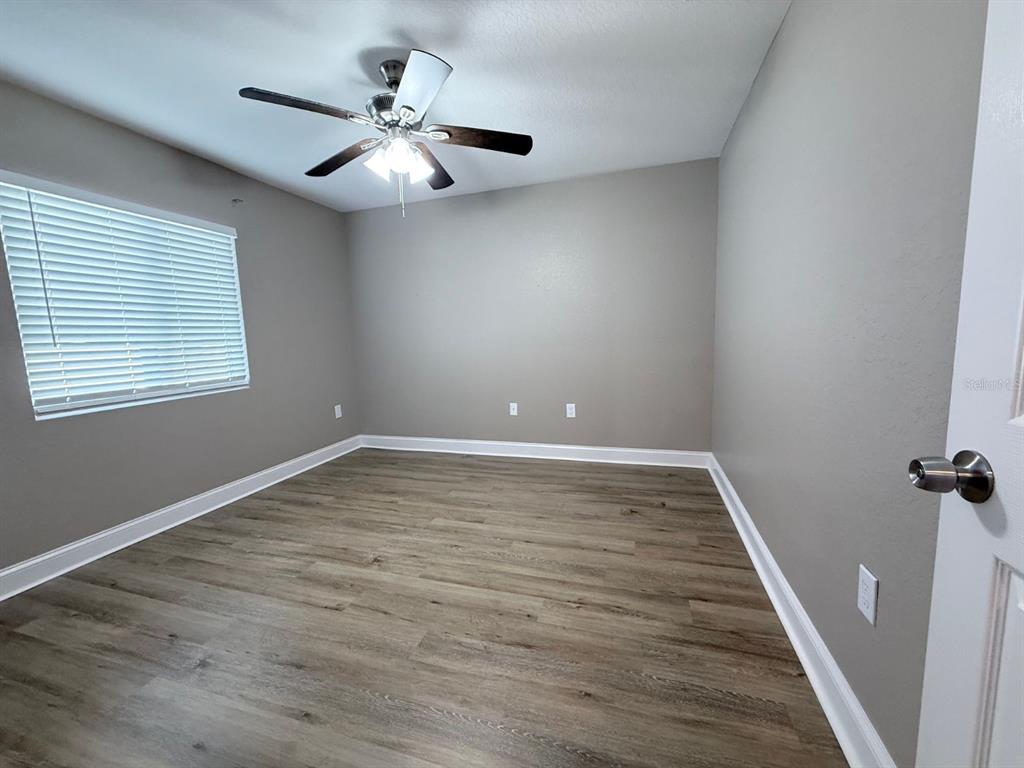 An empty bedroom features light gray walls, wood-look flooring, and a ceiling fan — 1139 SYCAMORE STREET, LAKELAND, FL