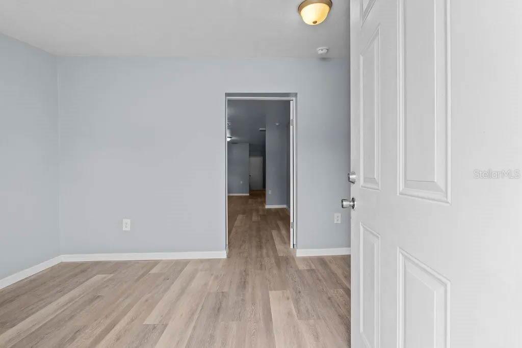 A room with light blue walls, wood-look flooring, and an open doorway leading to another room — 515 S CHARLESTON AVENUE, FORT MEADE, FL